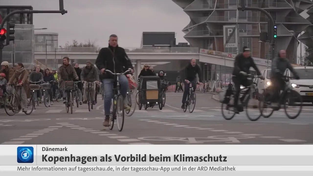 Breite Fahrradströmung an einer Kreuzung in Kopenhagen mit vielen Radfahrenden und Lastenrädern.