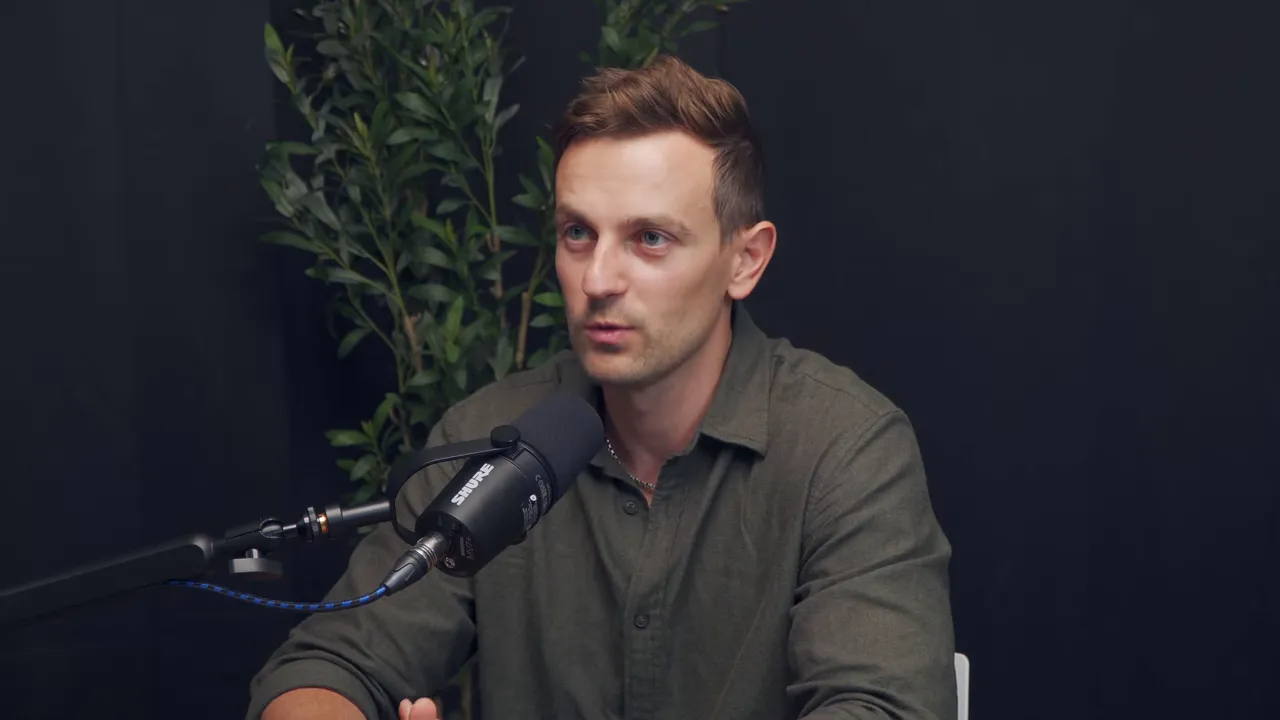 Кирилл в зелёной рубашке говорит в микрофон и жестикулирует в студии