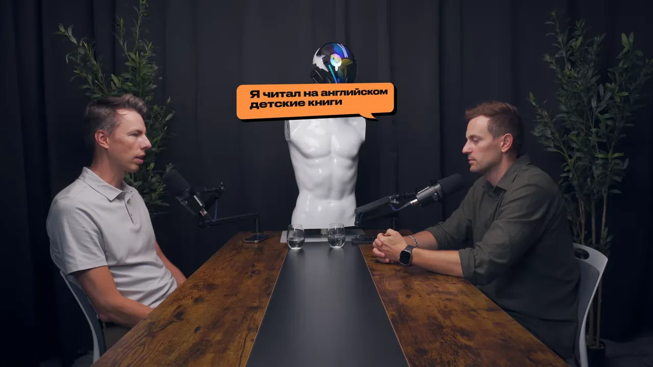 Широкий план двух собеседников за столом; над манекеном видно оранжевое облачко с текстом о чтении детских книг.