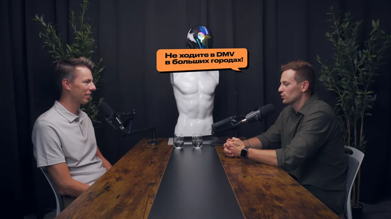двое мужчин в подкаст-студии сидят за столом; в центре манекен с оранжевым текстовым баллоном «Не ходите в DMV в больших городах!»