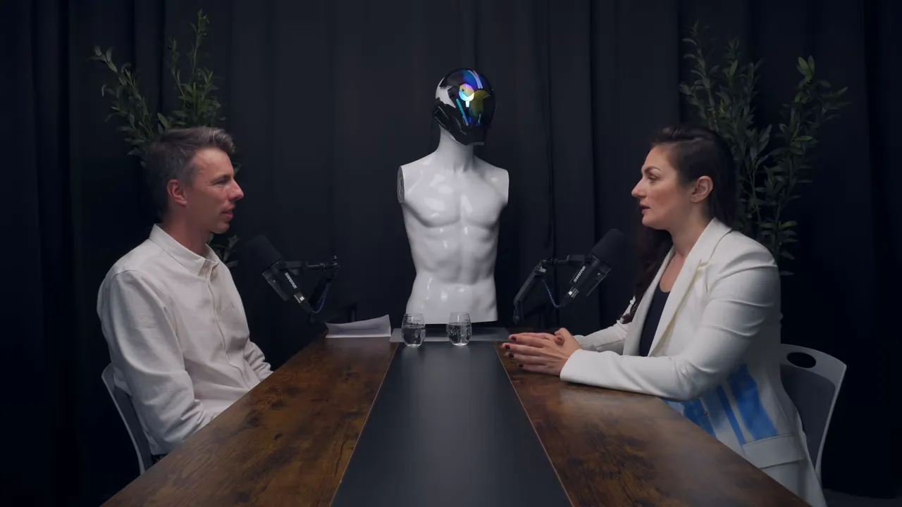 Широкий кадр: два спикера за столом с манекеном-роботом между ними в студии