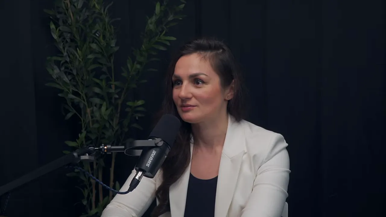 Марина Морган в белом пиджаке у микрофона, говорит о культуре и опере