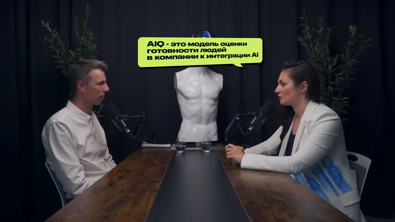 Широкий план интервью с речевой выноской «AIQ — это модель оценки готовности людей в компании к интеграции AI» над манекеном-роботом