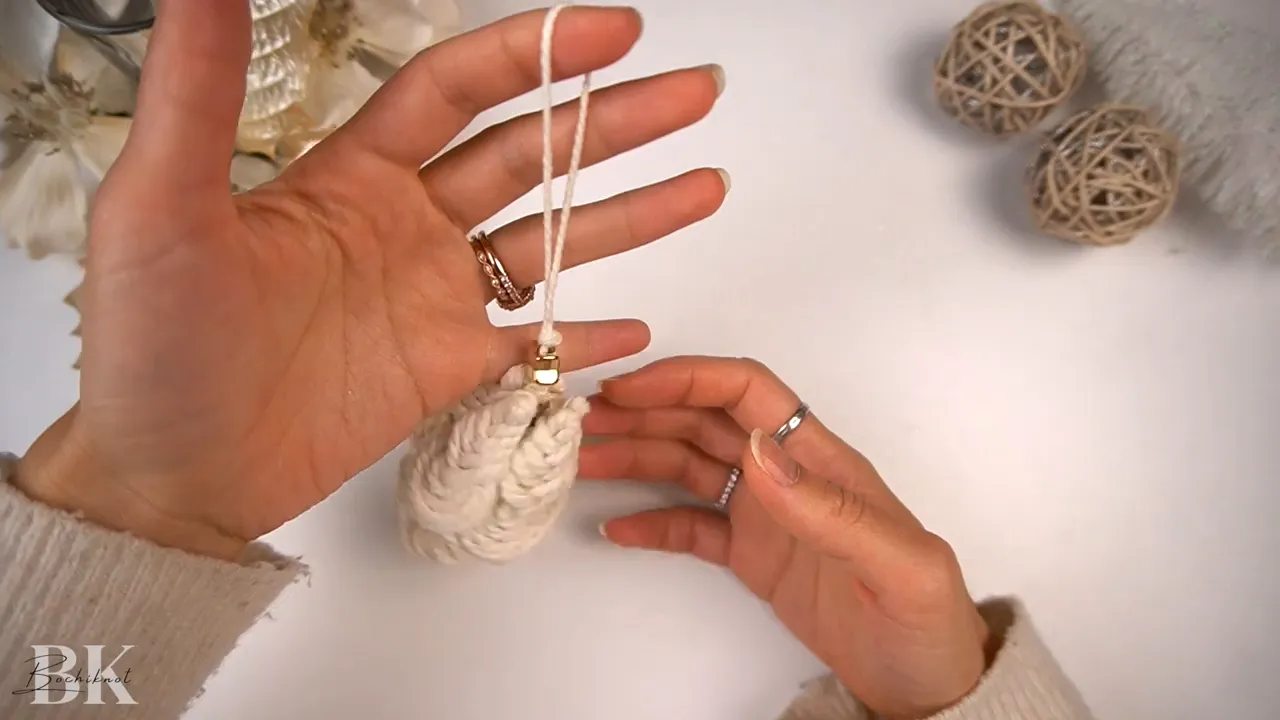 Finished small macrame tree ornament held by hands showing the hanging loop and star bead on top