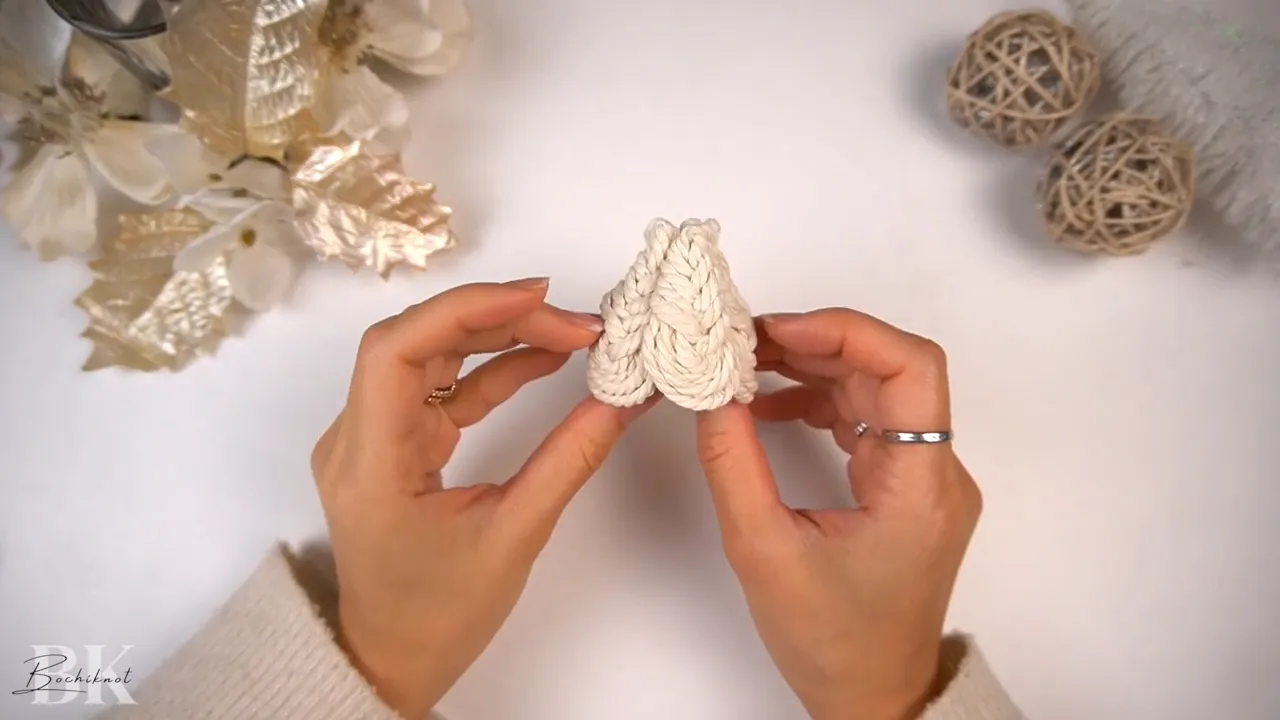 Five macrame Pipa knots arranged into a small triangular tree shape held between hands.