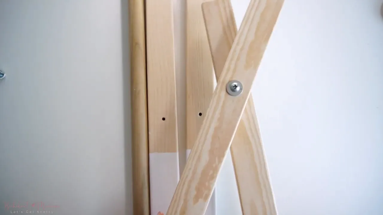 two wooden legs crossed and fastened with a screw and washer to create a hinged side frame
