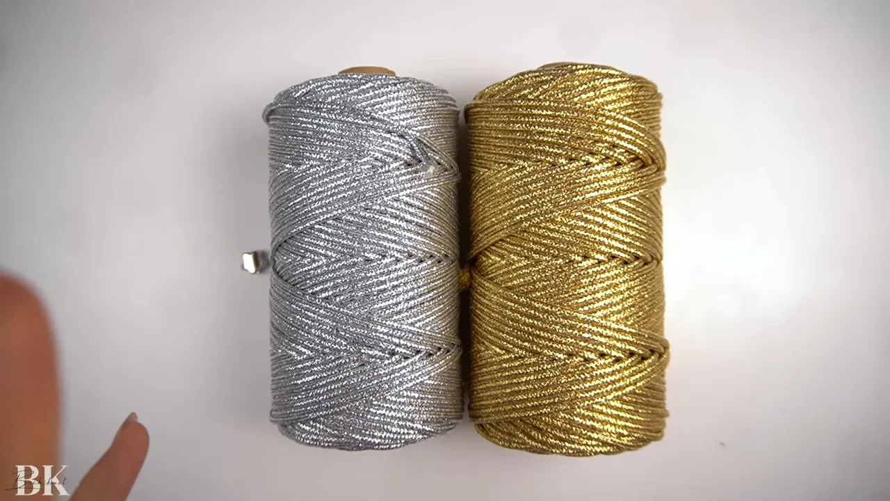 Two clear spools of metallic 3mm macrame cord, one silver and one gold, on a white background