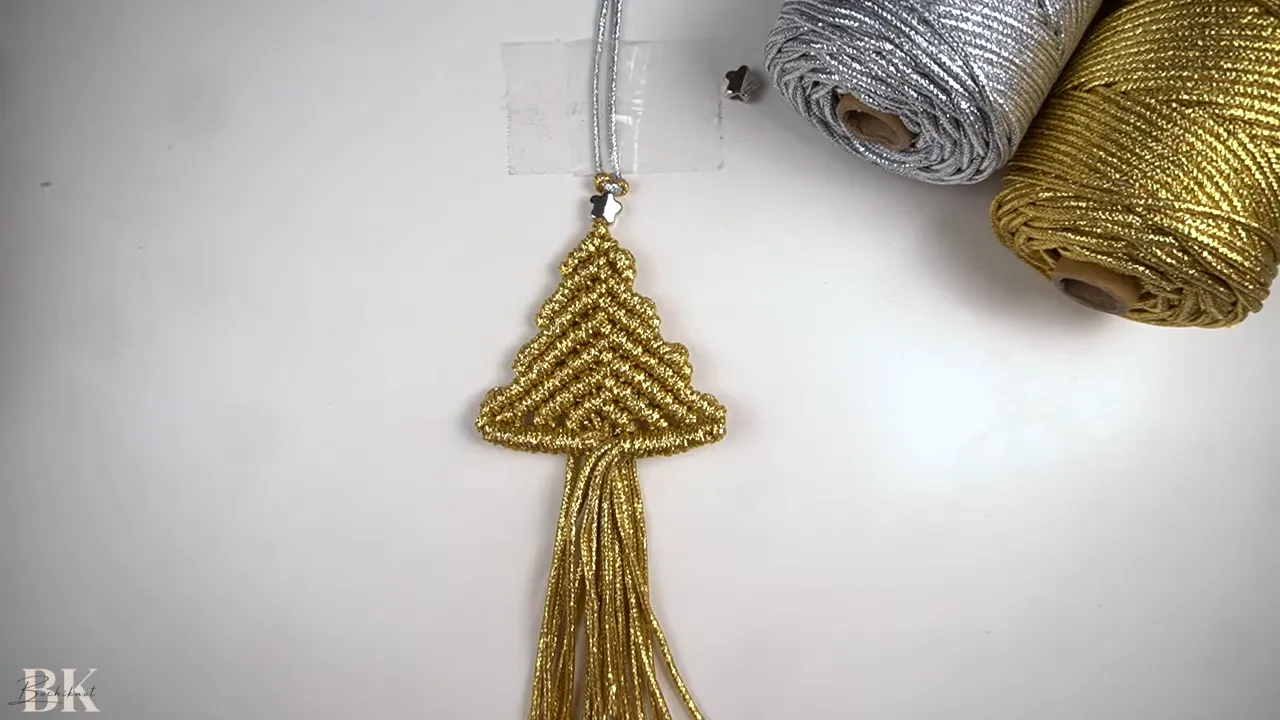 Gold macrame Christmas tree ornament with long fringe and spools of metallic cord