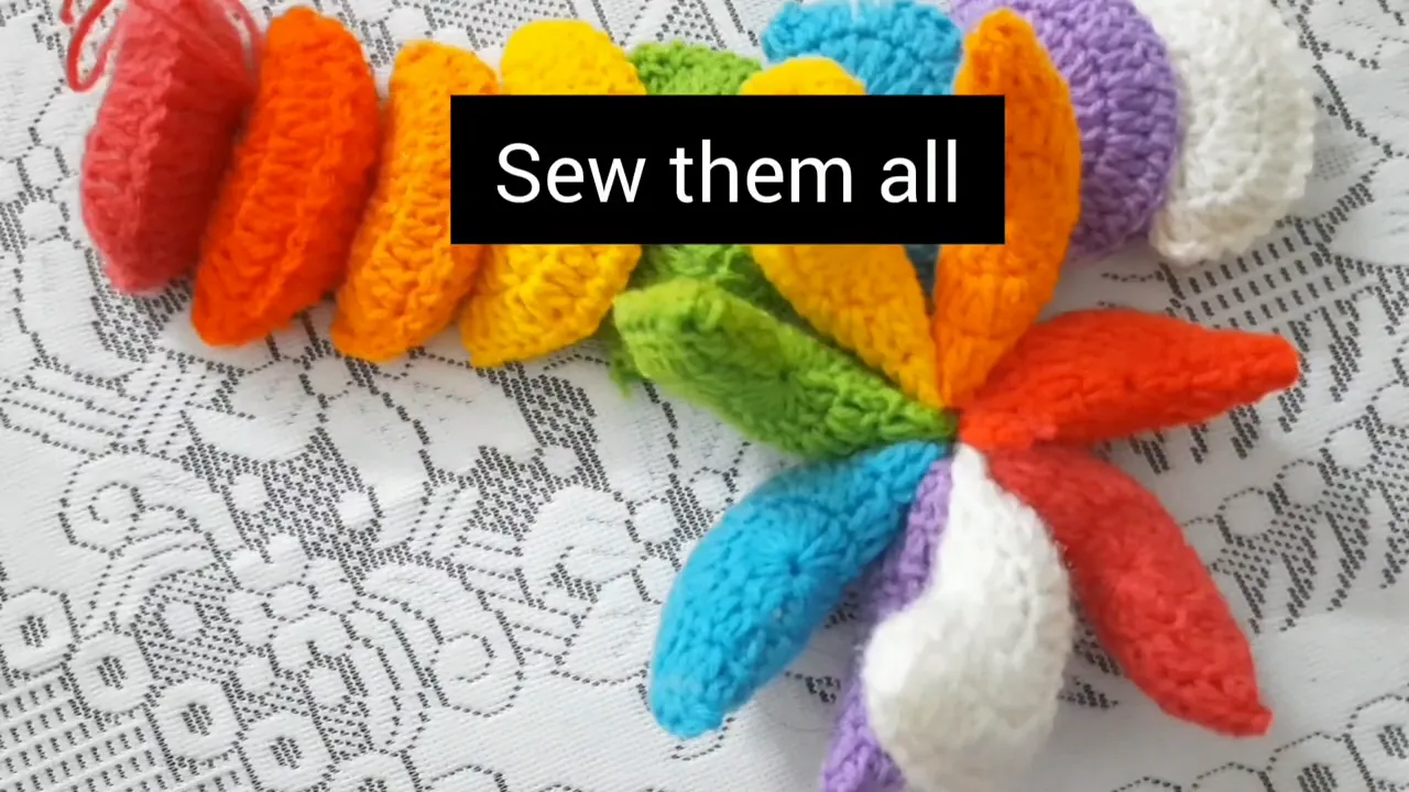 Eight colorful stuffed crochet motifs radiating from a sewn central point