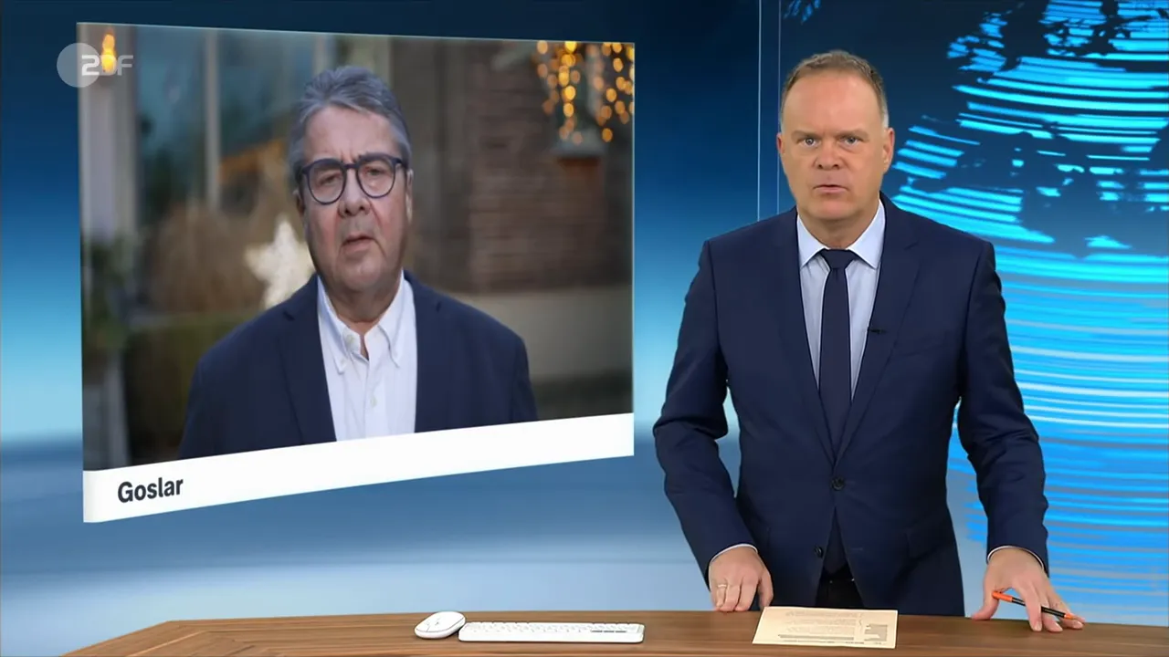 Fernsehstudio: Moderator frontal am Pult, zugeschalteter Gast links im Bildschirm