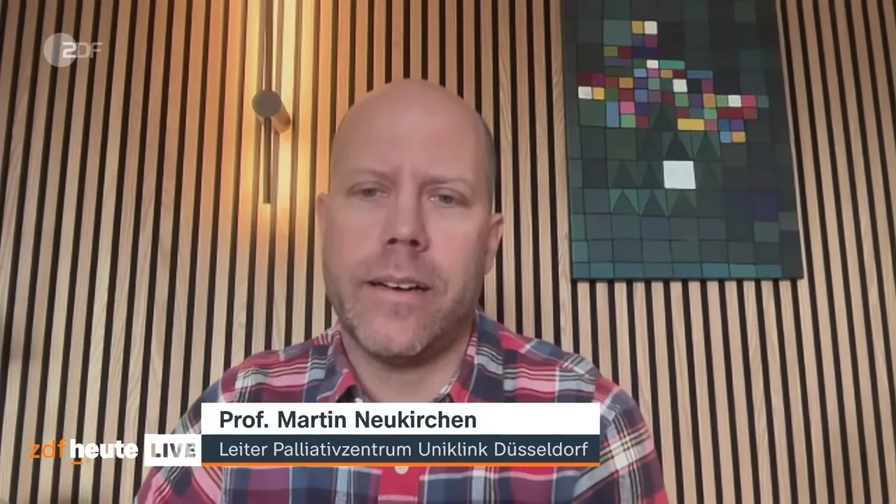 Klarer Videocall des Palliativmedizin-Experten vor vertikalen Holzlamellen mit sichtbarer Titelleiste