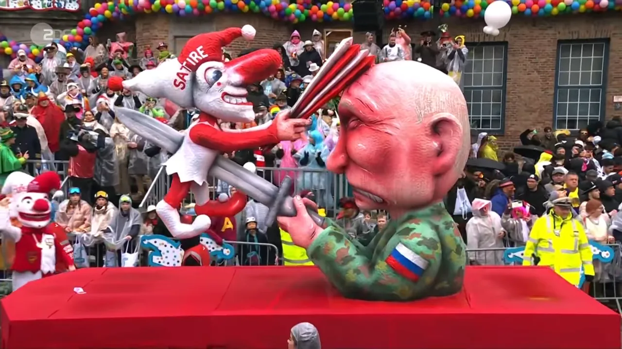 Satirischer Rosenmontagswagen mit überdimensionierter Karikaturfigur und Publikum im Hintergrund