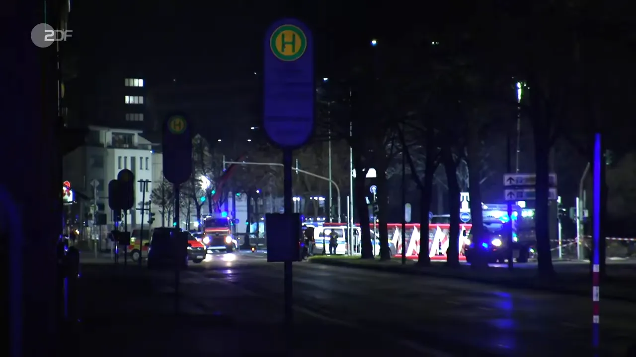 Nächtliche Szene: Rettungswagen, Polizeiwagen und abgesperrte Bushaltestelle mit Blaulicht in Gießen.
