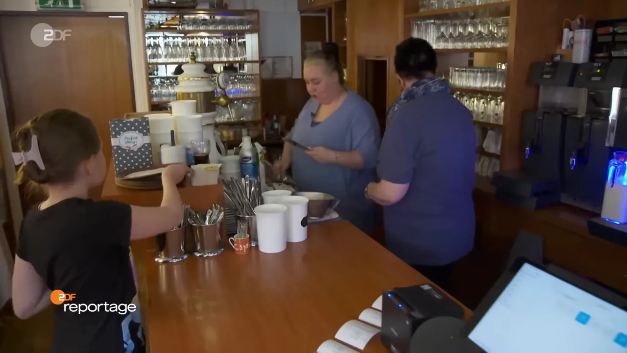 Innenansicht eines Cafés mit Personal hinter der Theke beim Vorbereiten von Bestellungen