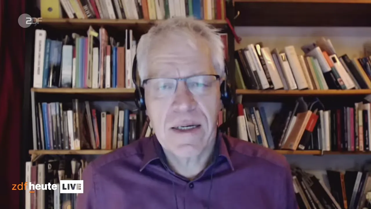 TV-Interview: Experte vor einem Bücherregal spricht über die Ölblockade gegen Kuba.