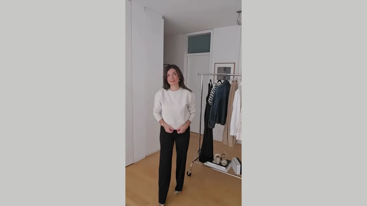 woman wearing light beige cropped sweatshirt with black trousers in a mirror-style vertical shot