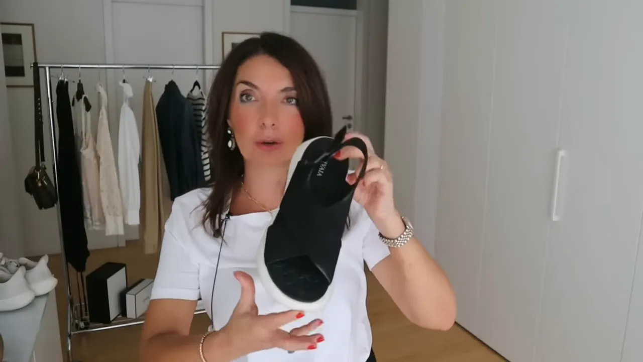 black sandal with white sole held up in front of camera