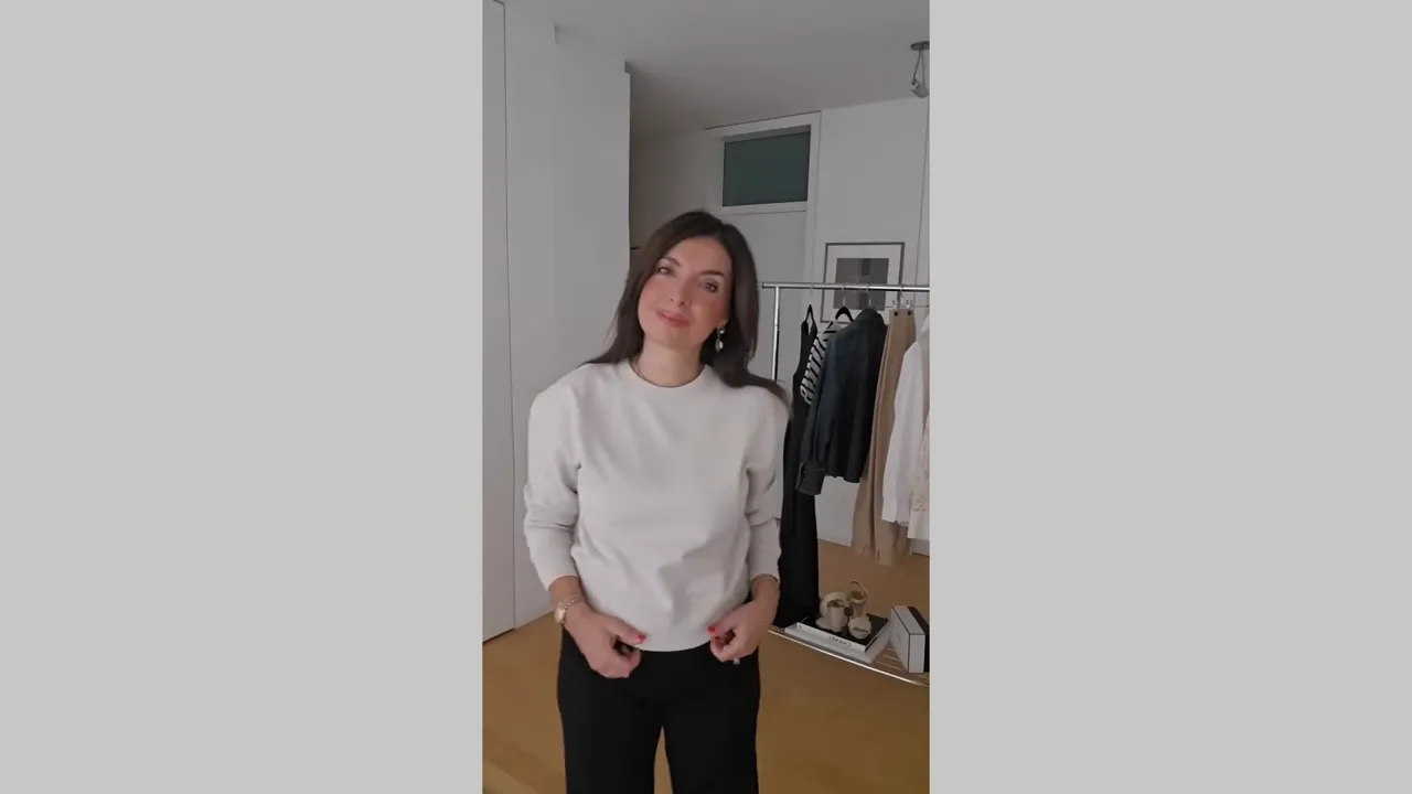 look con felpa chiara e pantaloni scuri mostrato a figura intera