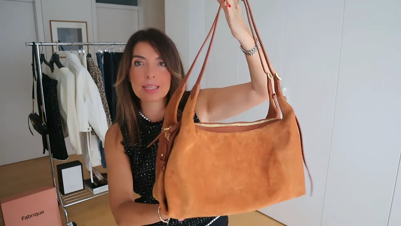 Warm brown suede shoulder bag held up to show its shape and double straps