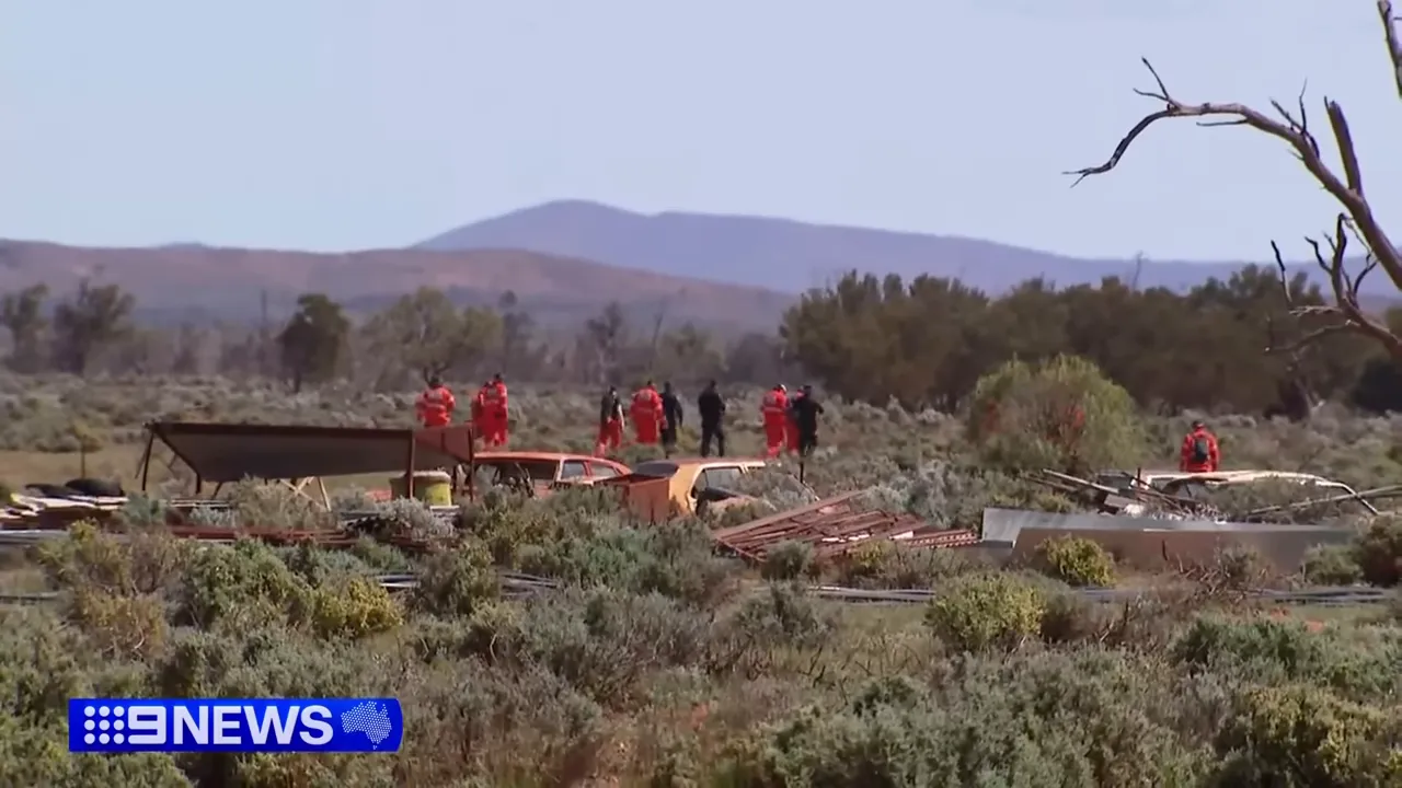 Police officers and volunteers searching scrubland north of the property