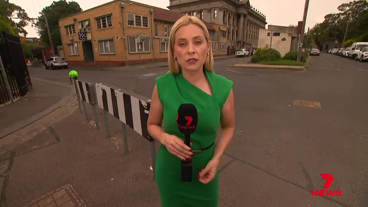 News reporter standing outside Fitzroy Police Station near the shooting scene