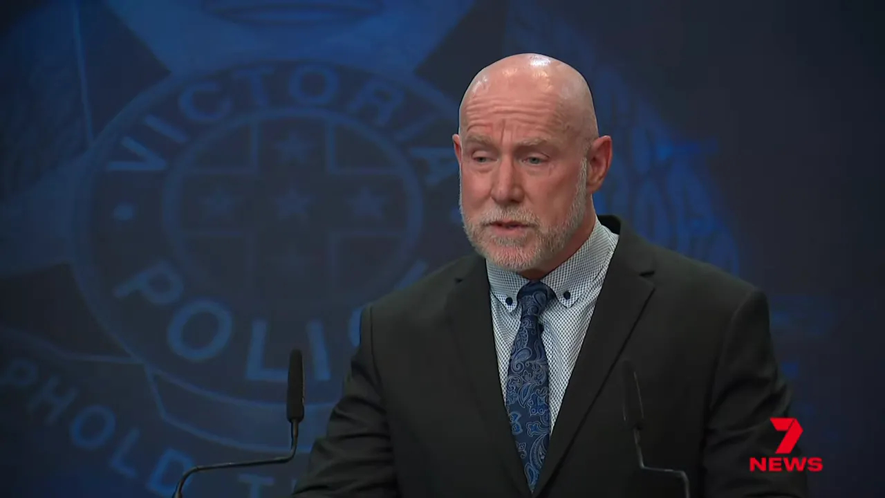 Police spokesperson speaking at a press conference with police insignia behind him.