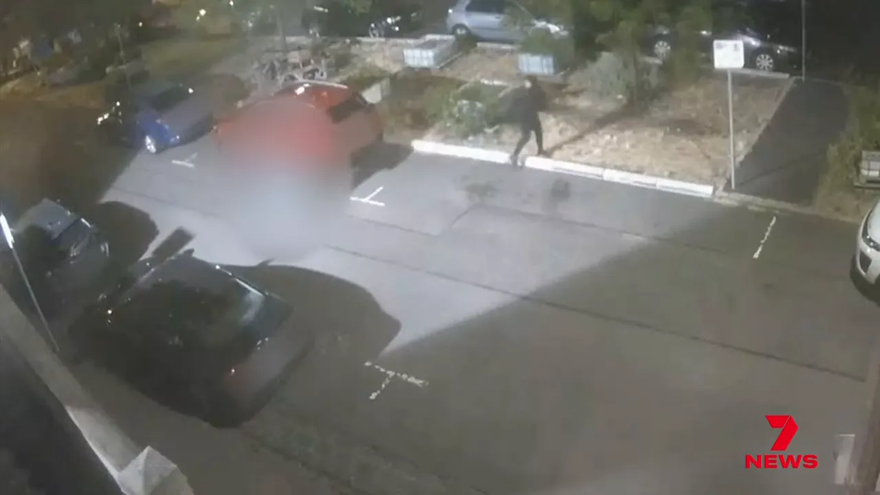 CCTV still of two figures walking on the footpath near parked cars outside Fitzroy Police Station at night