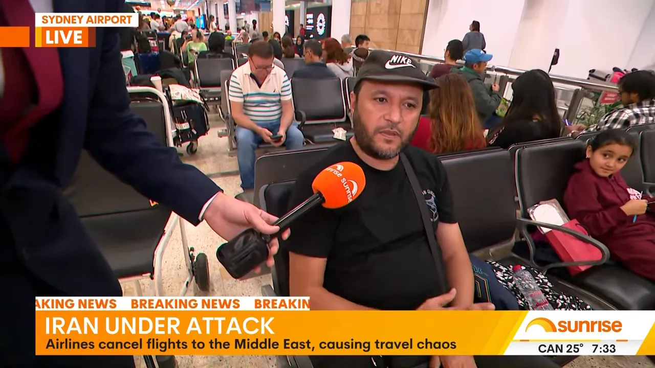 Passenger being interviewed in an airport terminal, Sunrise microphone pointed at him and other stranded passengers seated behind.