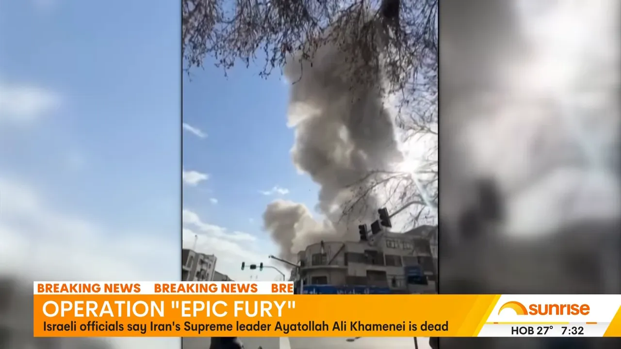 Thick smoke billowing above buildings and traffic lights under a blue sky