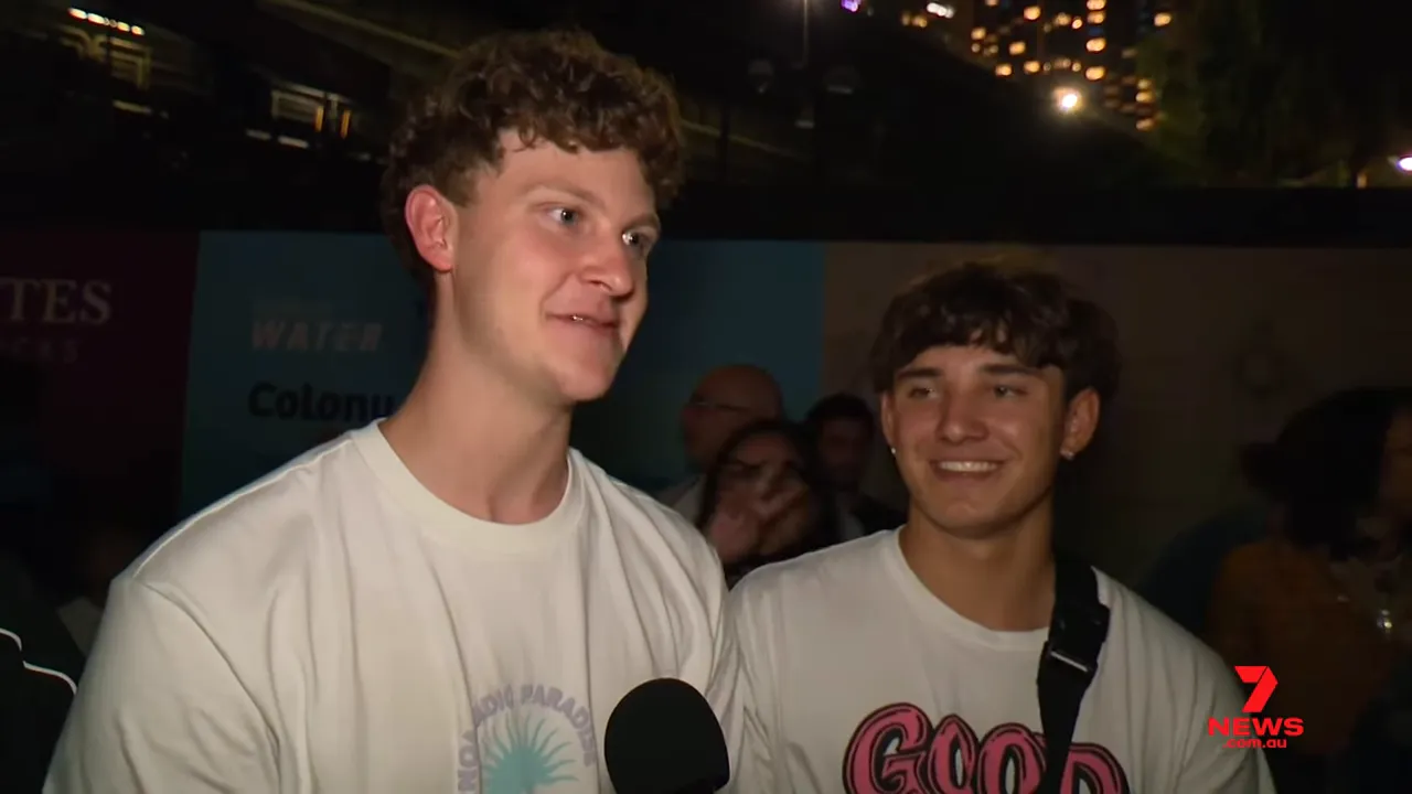Two smiling young men interviewed by news media at Sydney New Year's Eve crowd