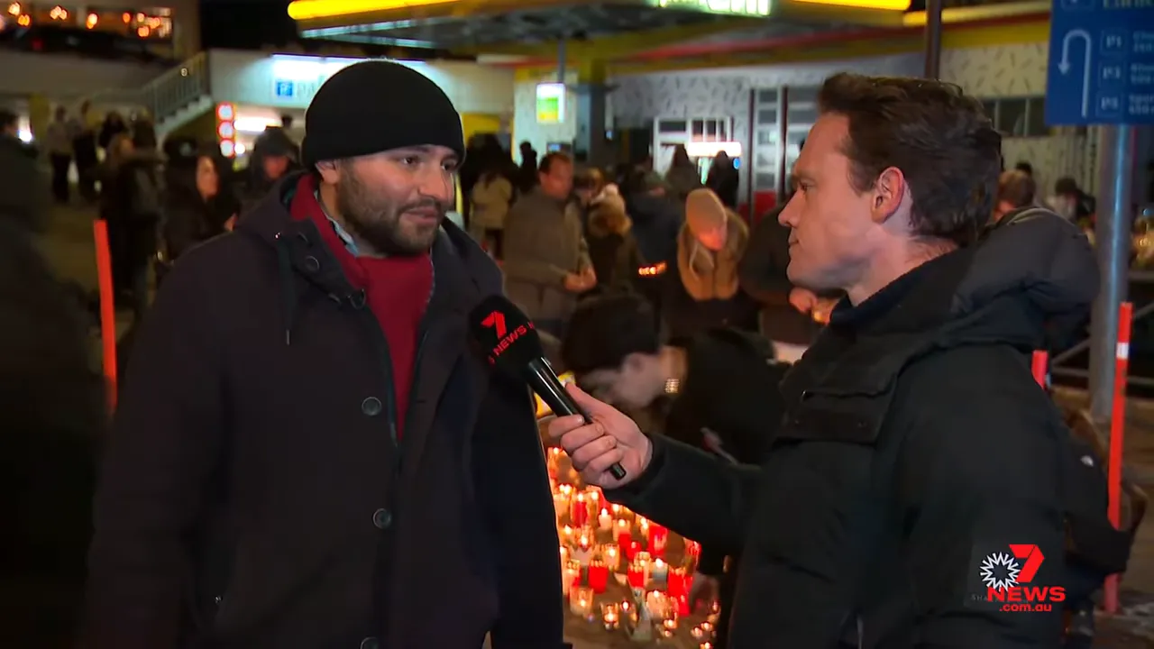 Eyewitness interviewed by a reporter with a candle memorial and crowd behind them after a resort incident.