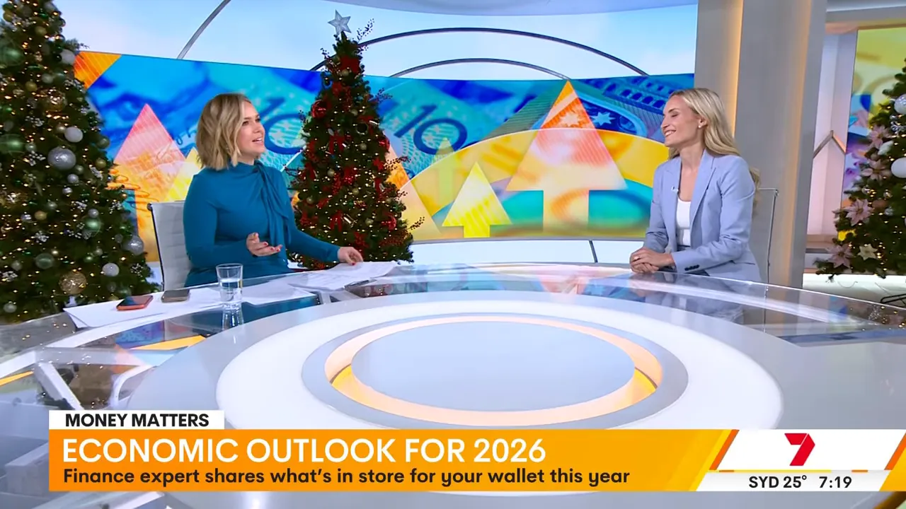 Wide television-studio shot showing hosts at a desk with an 'Economic outlook for 2026' chyron and financial graphics in the background