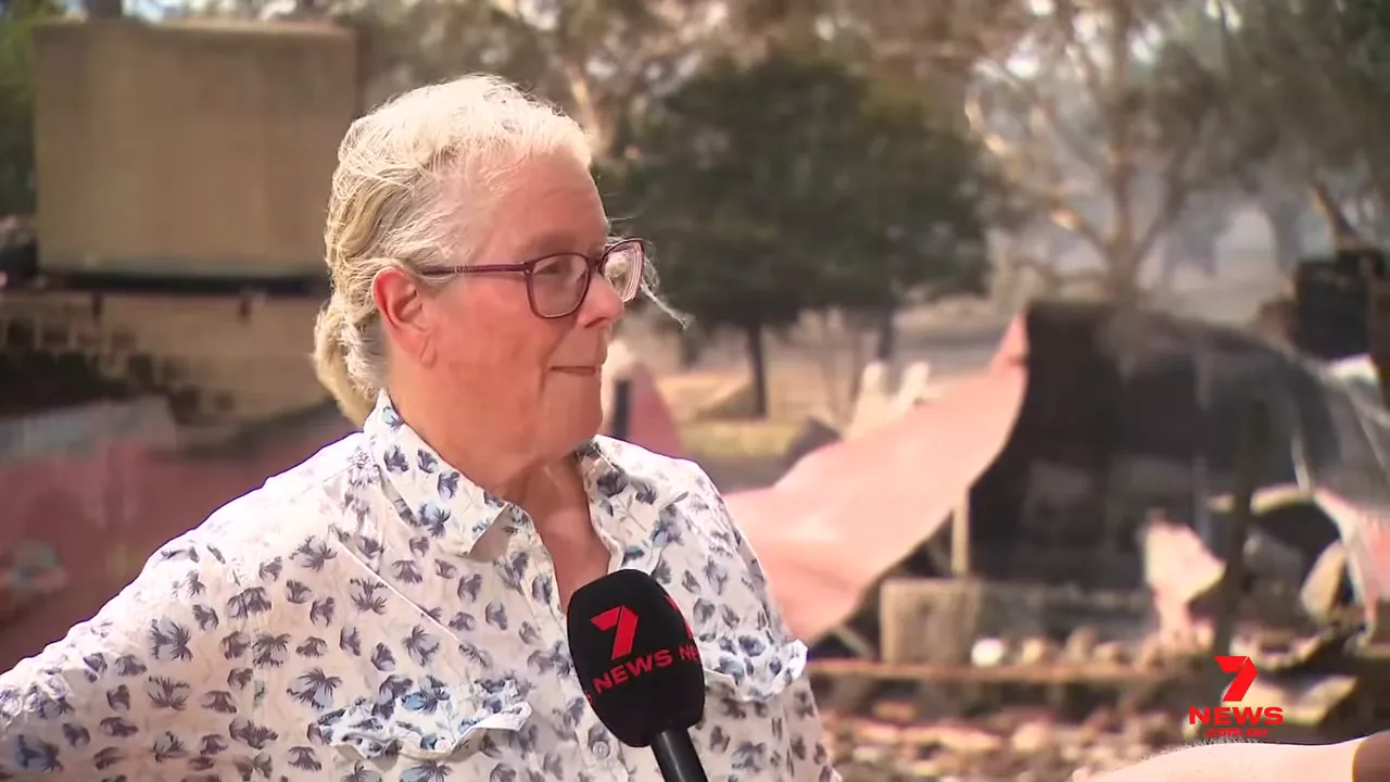 Interviewee standing in front of collapsed shed and fire-damaged property