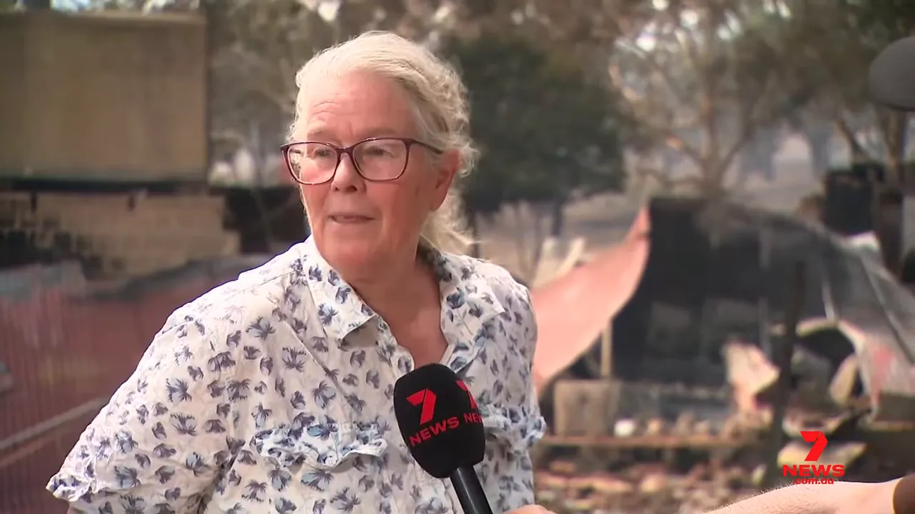 Woman interviewed by news reporter with charred shed and debris in the background
