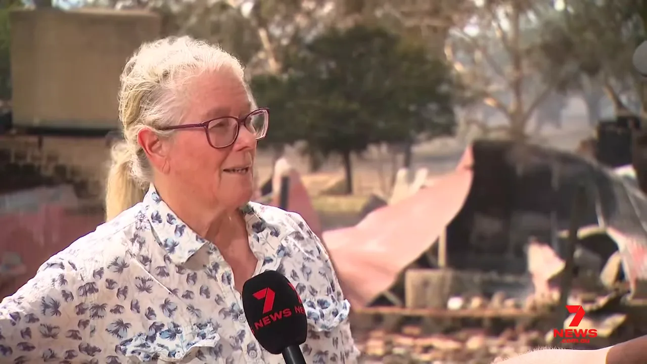 Homeowner interviewed in front of a charred shed roof and scattered debris, news microphone in frame