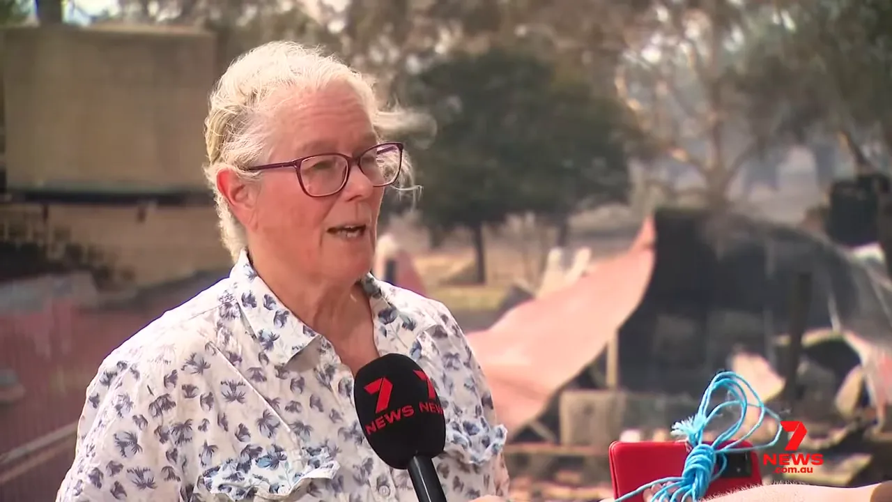 Clear interview shot of the homeowner with a Seven News microphone and burnt shed in the background