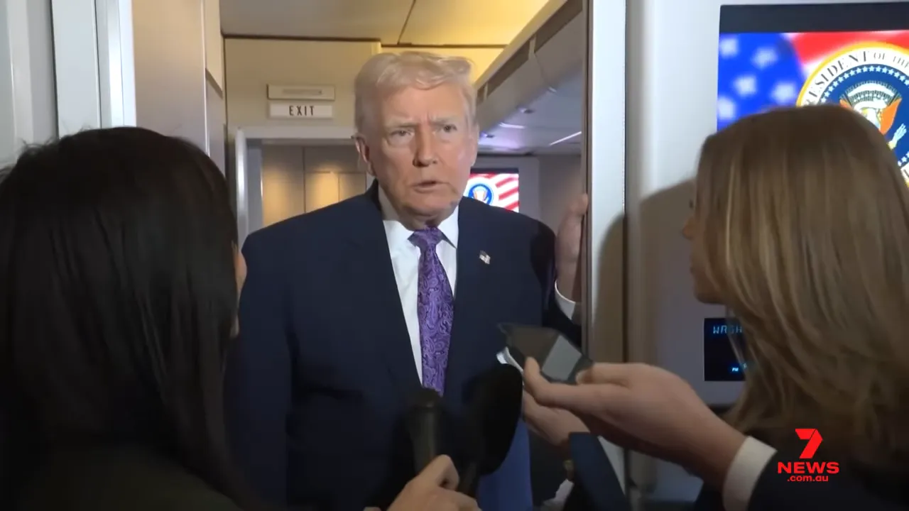 President speaking to reporters on a plane, framed by reporters' microphones and the cabin interior