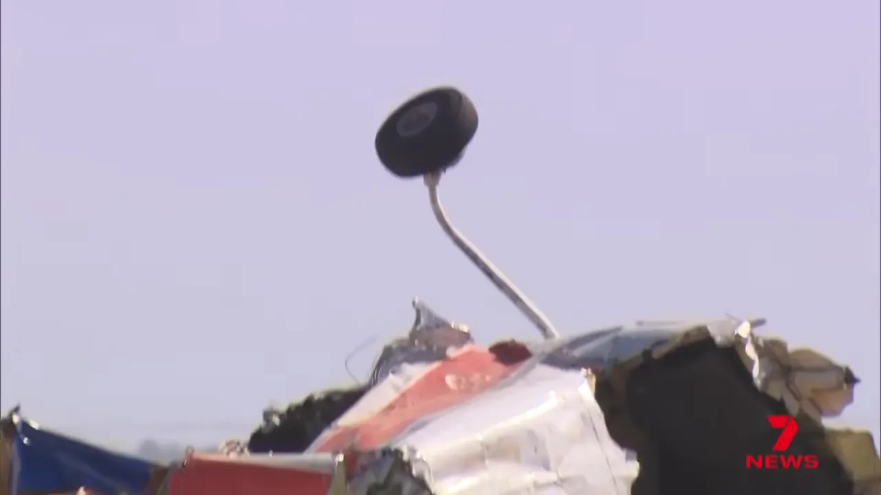 Detached landing gear wheel protruding from a crushed section of the aircraft fuselage