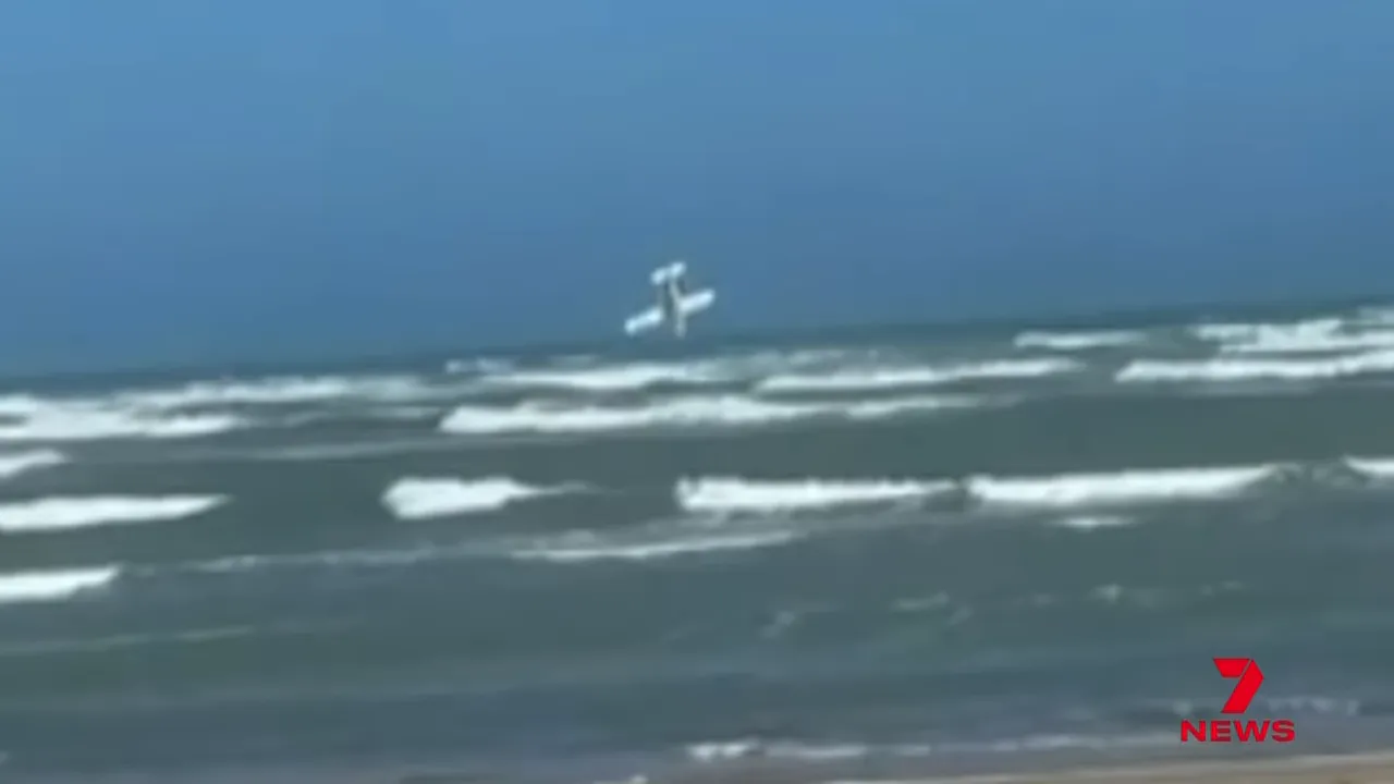 Cessna 210 captured in a steep nose-down roll over the ocean with waves beneath.
