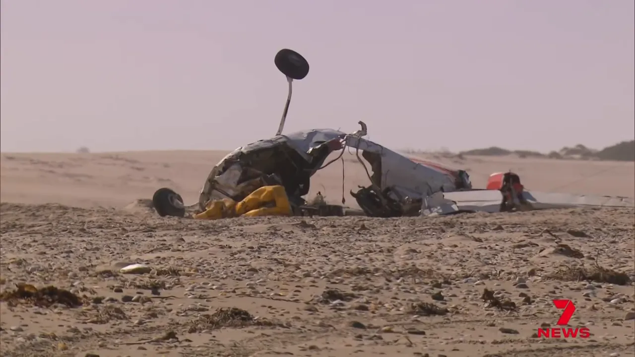 Cessna 210 wreckage on sandy beach with upright landing gear and debris