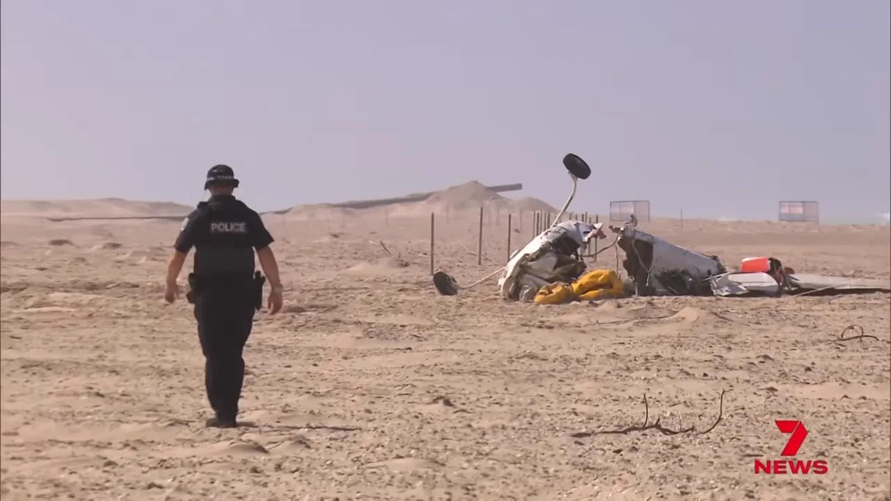 Police officer walking toward Cessna 210 wreckage on a sandy beach
