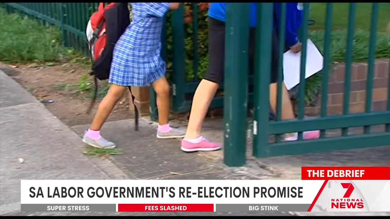 schoolchildren's legs and backpacks as they walk through a green school gate
