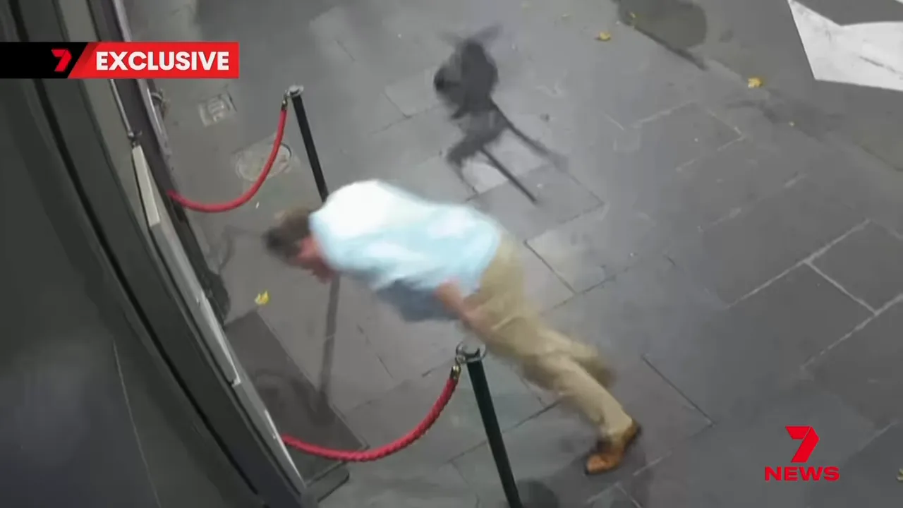 CCTV still showing a chair in mid‑air behind a man outside a venue, capturing the moment of impact.