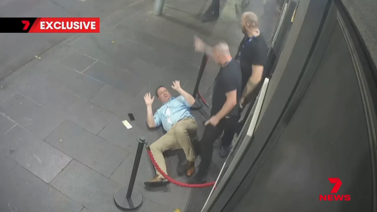 CCTV still of a man lying on the pavement with two security staff standing nearby outside a club