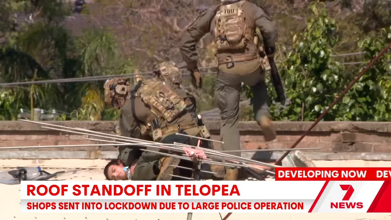 Close view of tactical officers pinning a man face-down on a rooftop during the Telopea standoff
