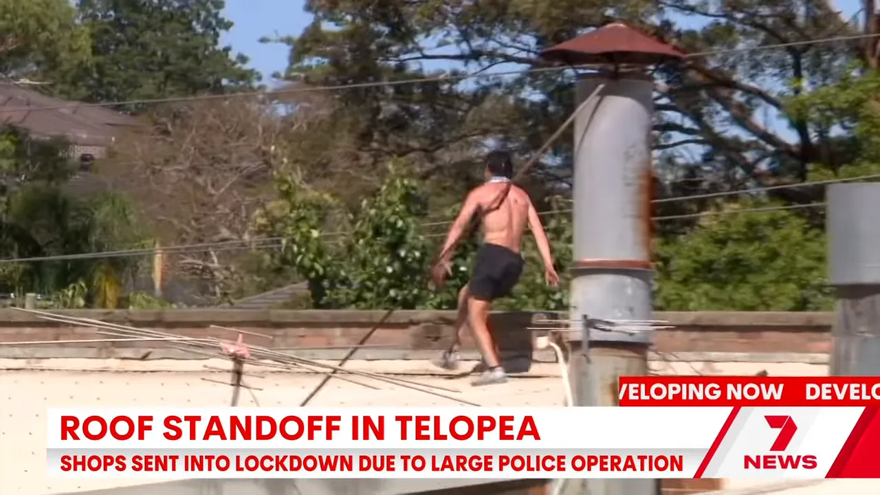 shirtless man pacing on a rooftop above shops in Telopea