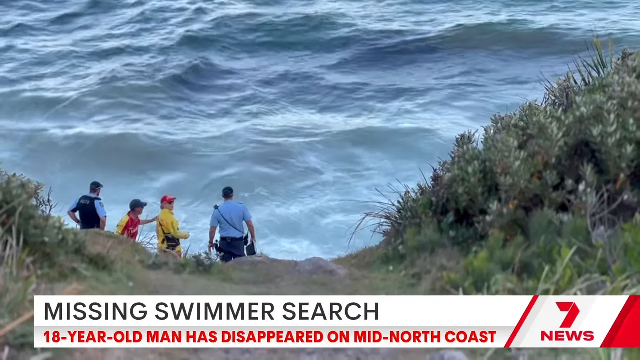 Group of rescue personnel and police on a coastal path looking toward choppy ocean waves at a rocky shoreline