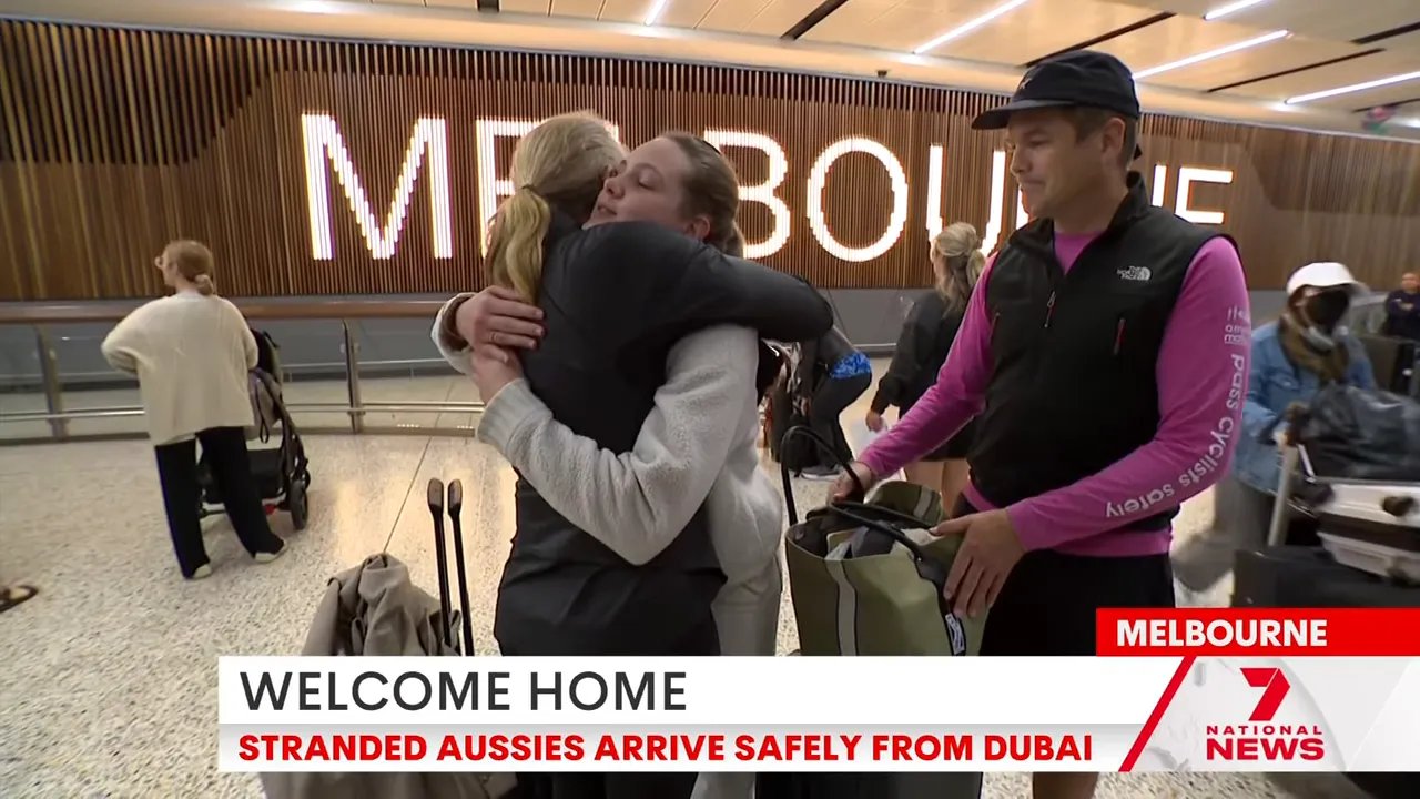 Passengers hugging in front of the illuminated 'MELBOURNE' sign at Tullamarine Airport with luggage nearby