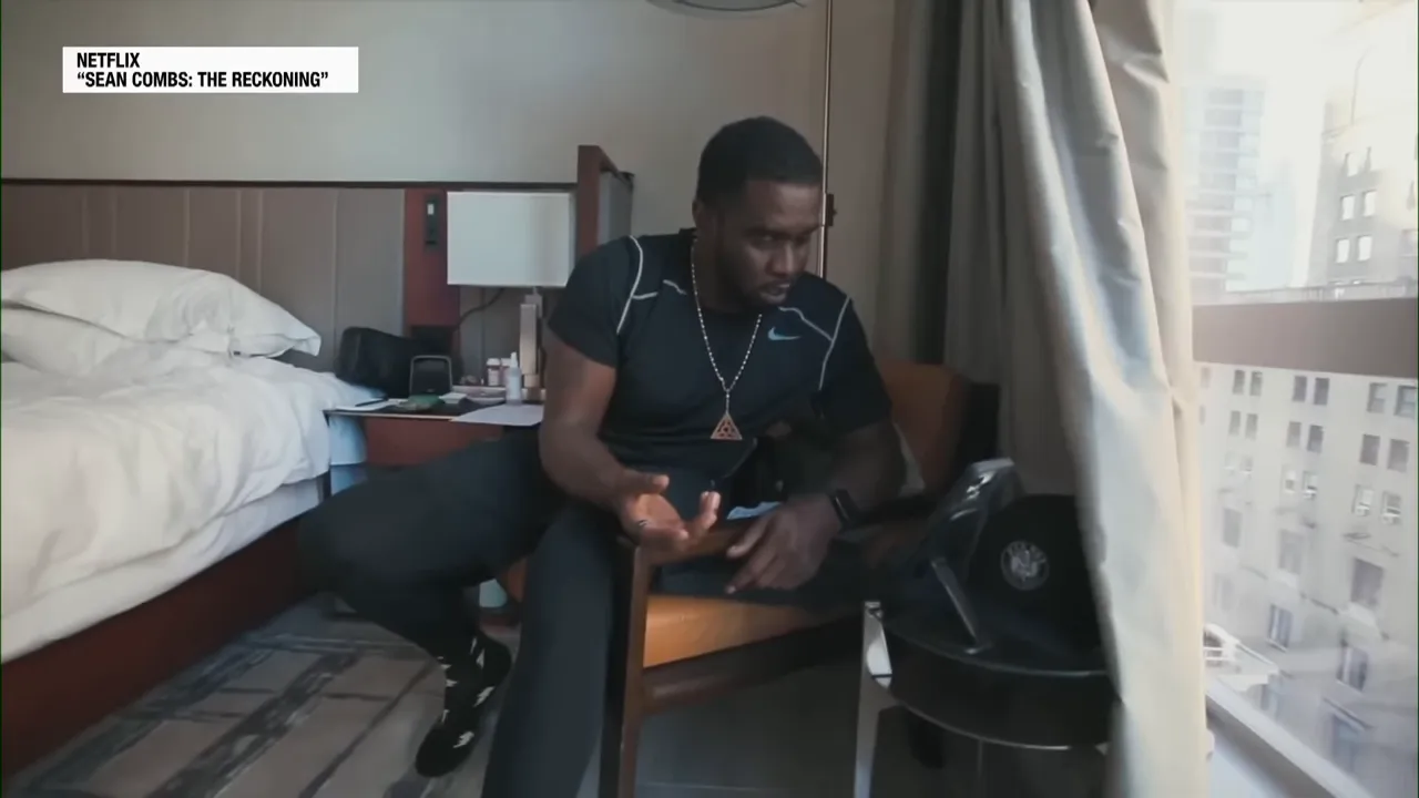 Screenshot from the Netflix documentary showing a subject seated in a hotel room making a tense phone call