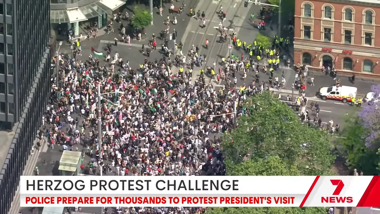 Aerial shot showing thousands of protesters packed into city streets near Town Hall with police and barriers visible